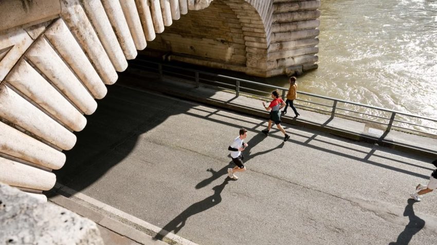 View of joggers running under the Pont de Bir-Hakeim in Paris, France during the day.